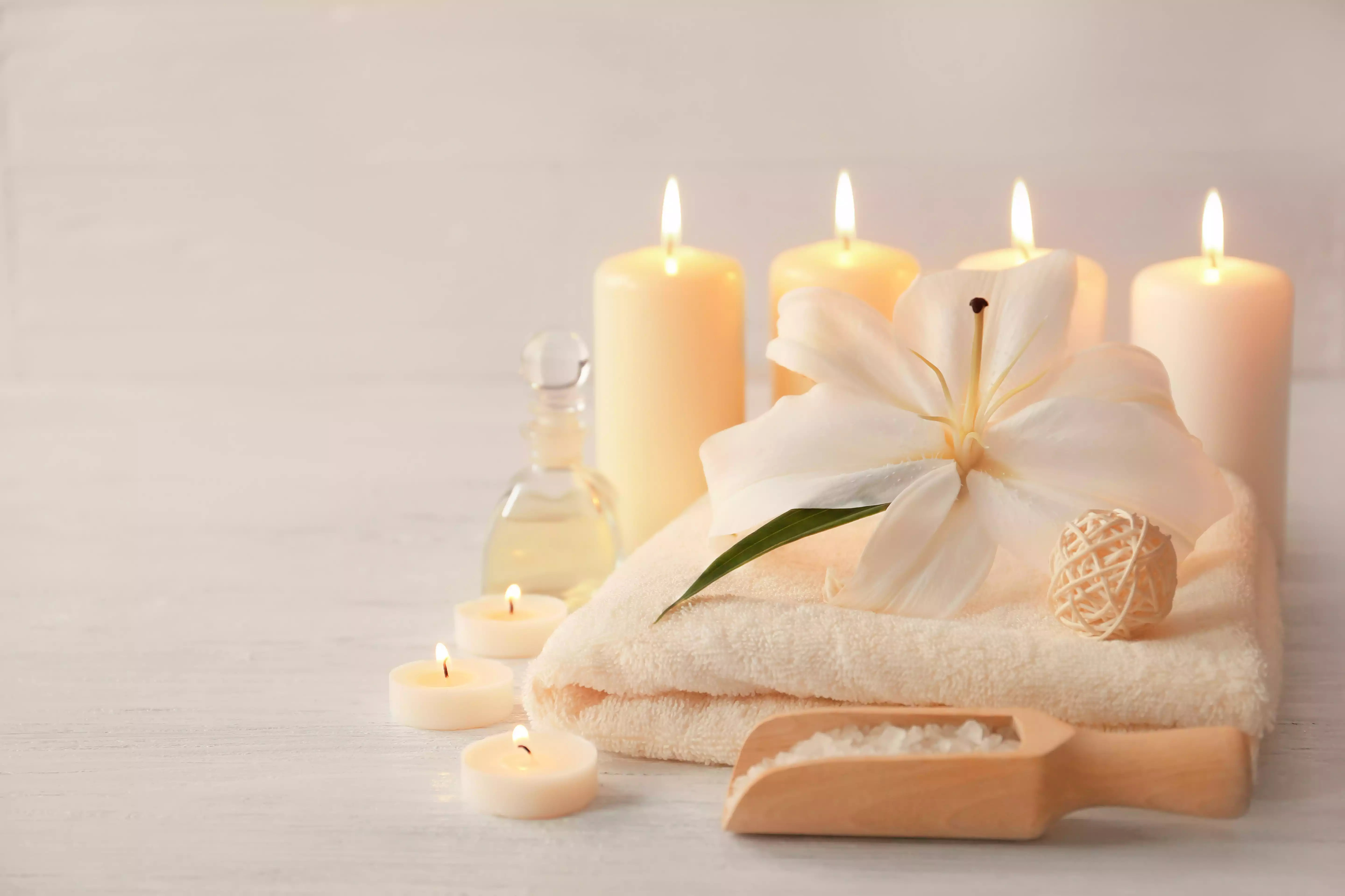 Composition spa apaisante avec serviettes blanches et bougies allumées évoquant l'univers de la réflexologie