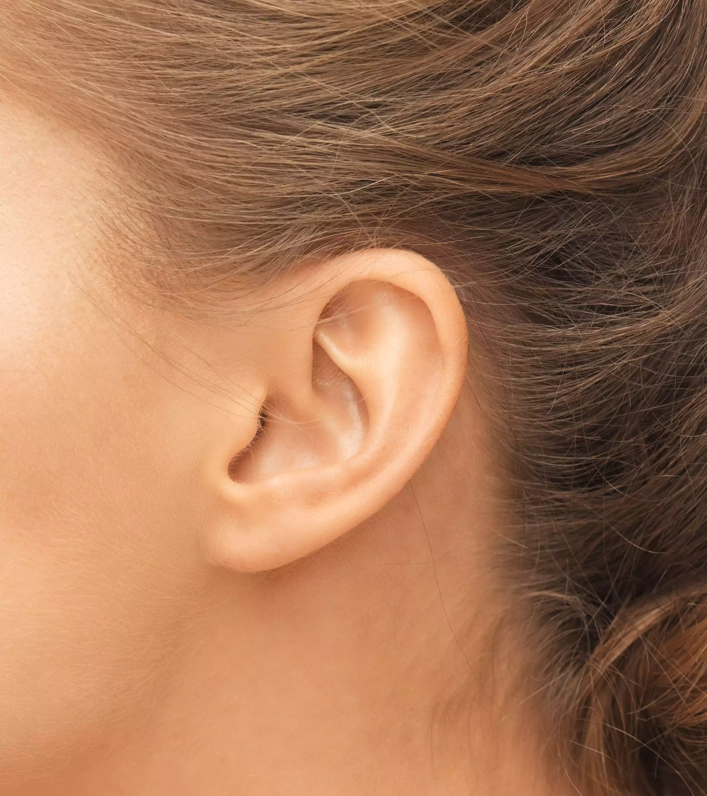 Gros plan sur l'oreille d'une femme, zone de travail lors d'une séance de réflexologie auriculaire
