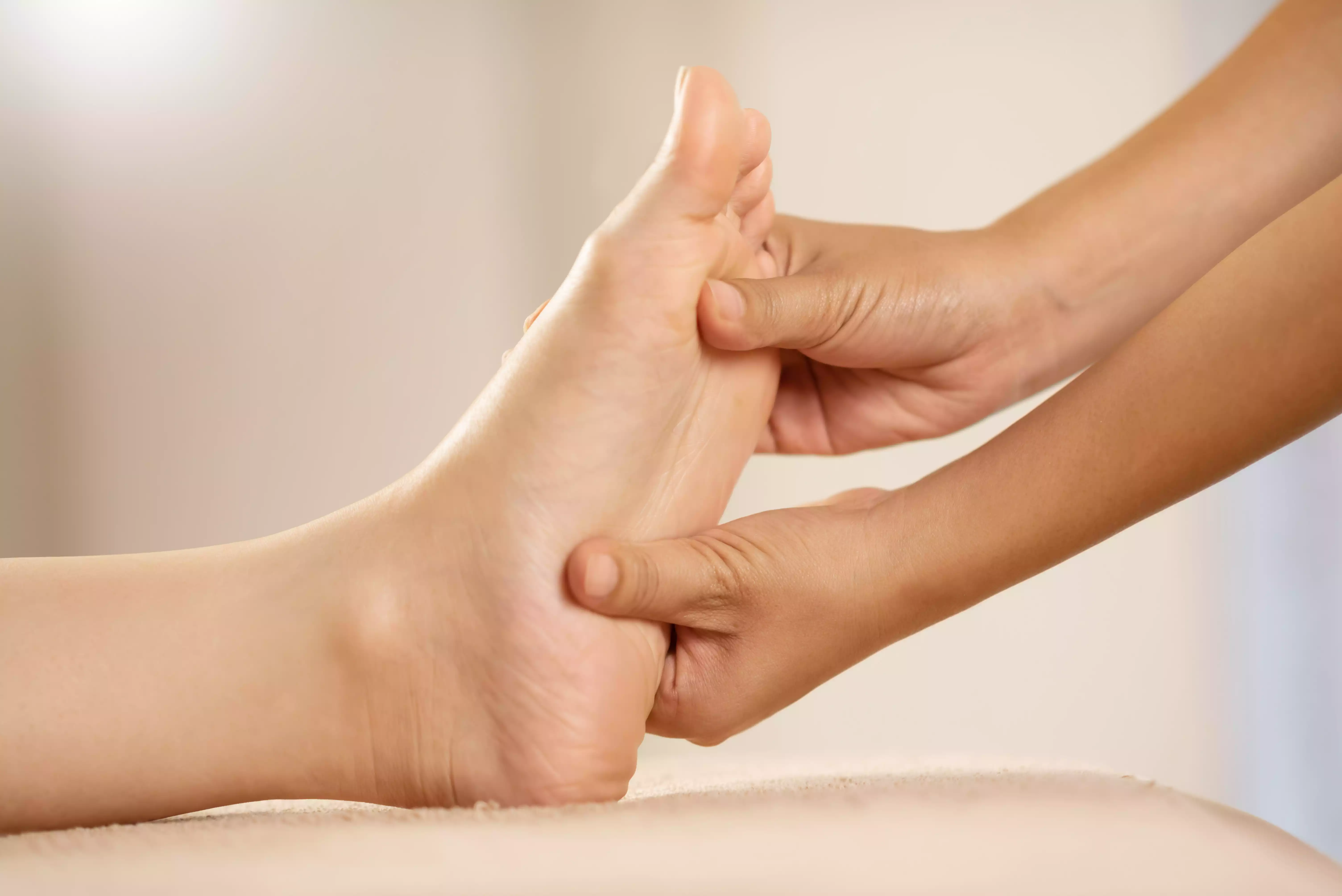 Praticienne effectuant un massage de réflexologie plantaire sur la plante d'un pied