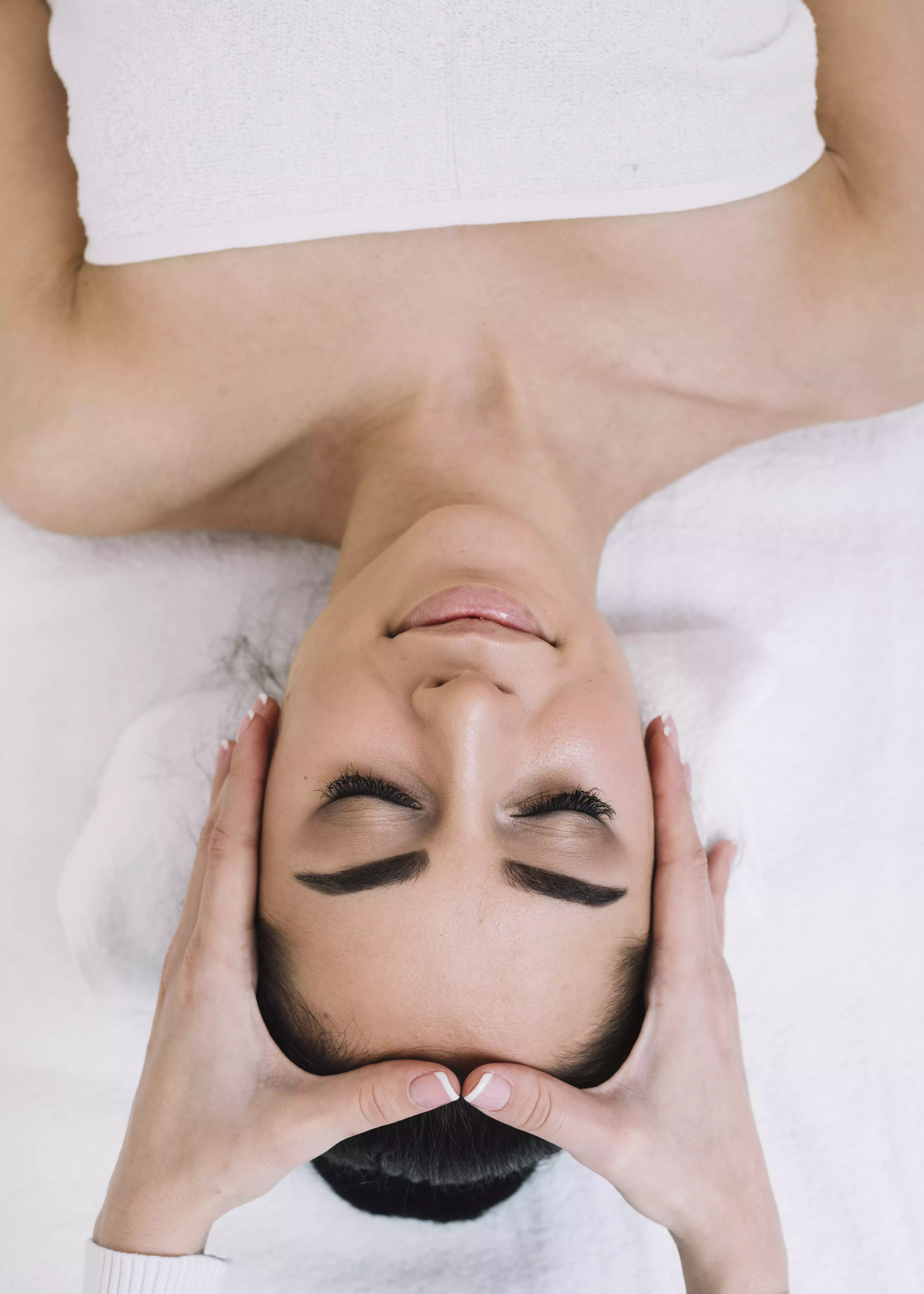 Femme recevant un massage crânio-facial, yeux fermés, en état de détente profonde